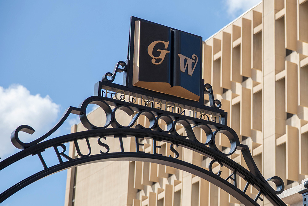 GW Trustee's Gate on a clear and sunny day with Gelman Library in the background