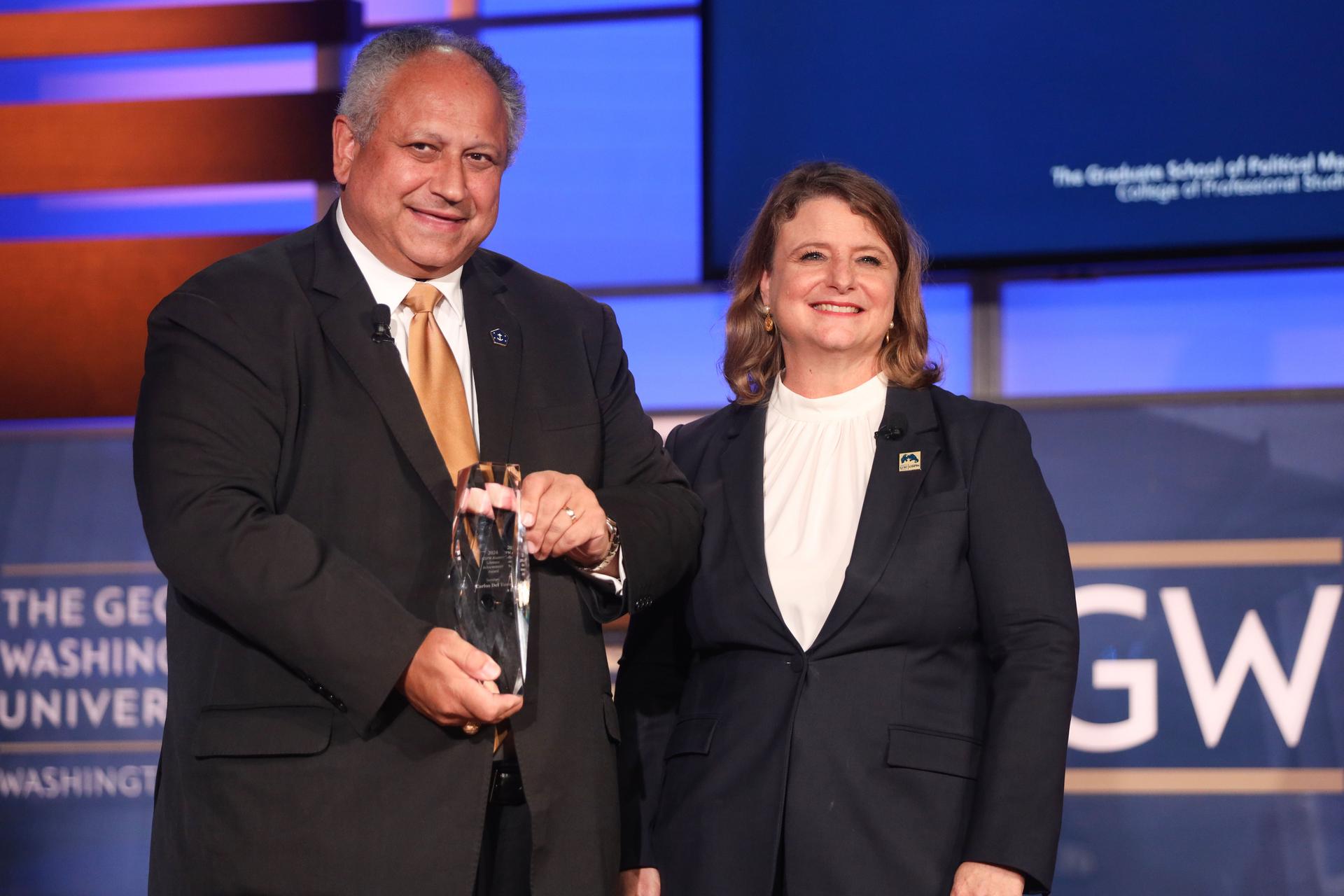 U.S. Navy Secretary Carlos Del Toro accepts the GSPM Alumni Lifetime Achievement Award presented by CPS Dean Liesl Riddle. (Lily Speredelozzi/GW Today)