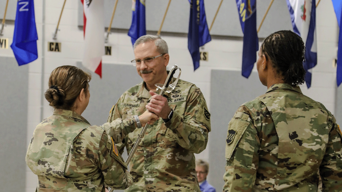Dan Fuhrman, MIPP ’15 receiving a saber in ceremony with two individuals.